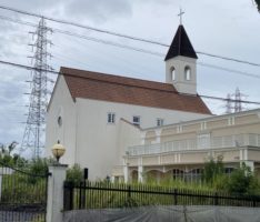 閉館した結婚式場の柵の中に雑草が伸びて荒れている