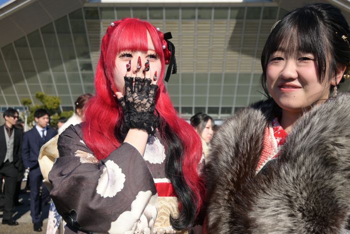 ネイルチップをつけた手袋をつけて振袖を着た赤い髪の女性