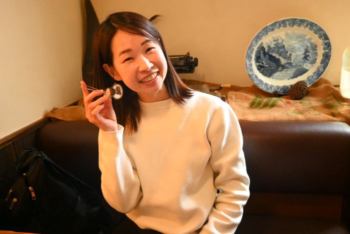 コーヒーゼリーのキーホルダーを持って微笑む伊藤さん
