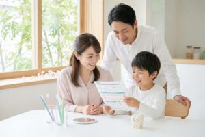 学校の歯科健診のプリントを笑顔で確認する家族の風景（かわむら歯科医院）